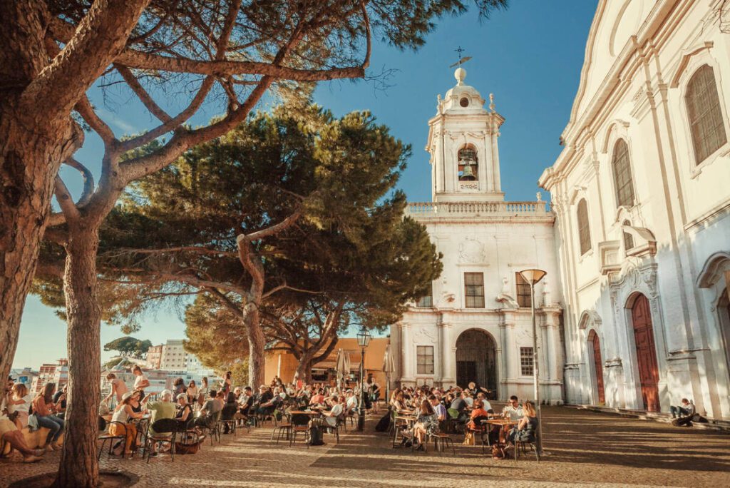 Lisbon, Portugal: Crowd of visitors of outdoor restaurant drinking and relaxing on terrace with beautiful city view on May 14, 2019. Alfama is the oldest district of Lisbon city