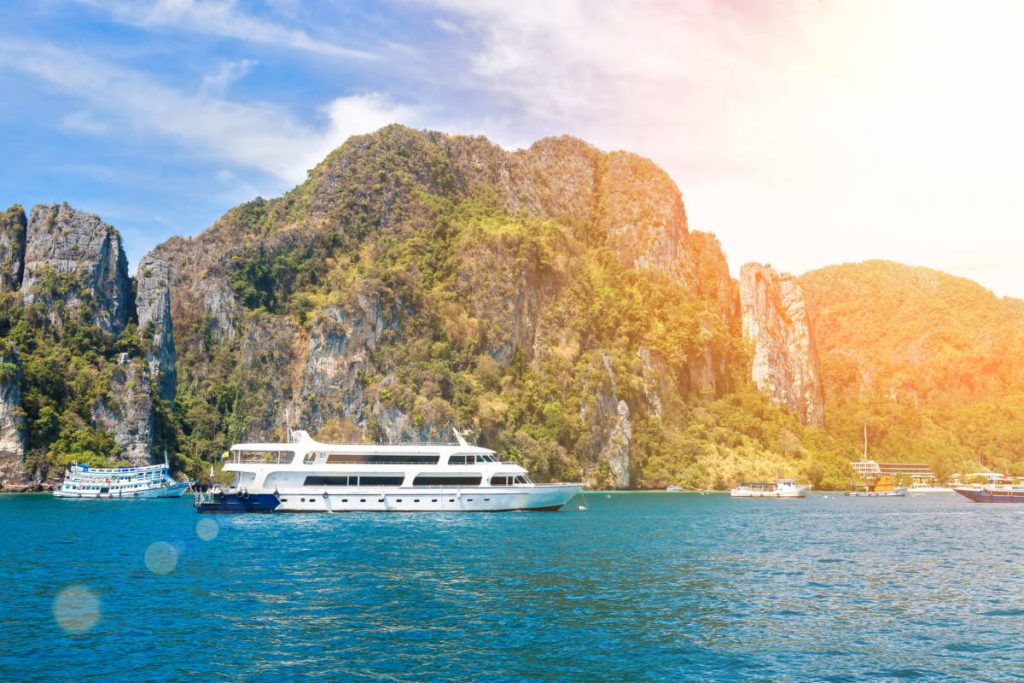 Small cruise ship in the waters of andaman sea with rocky island on background. At sunny day